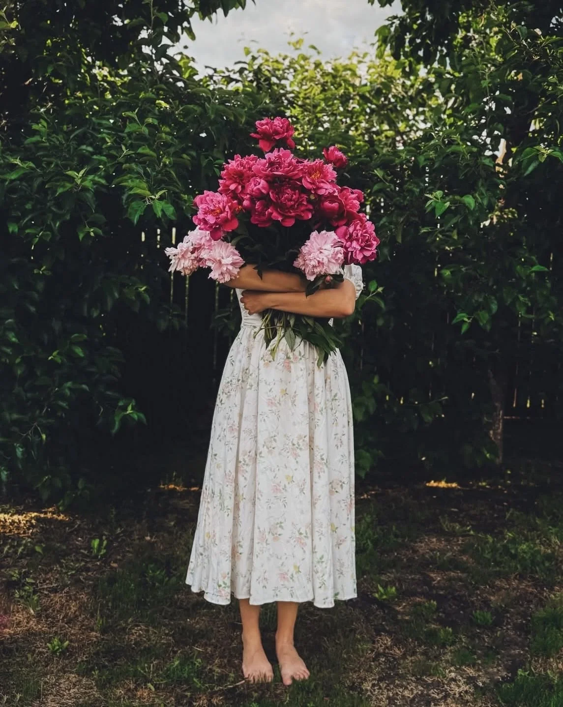 A gathered bouquet of magenta flowers held against a shaded garden.