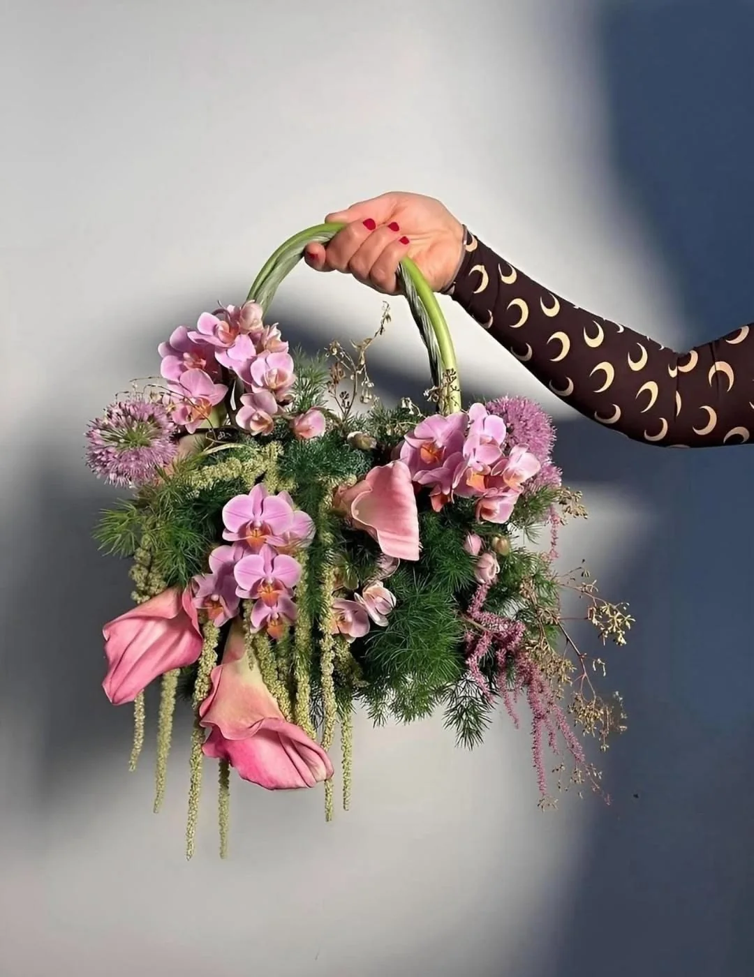 A curved green-stem handle with pink flowers and soft trailing botanical textures.